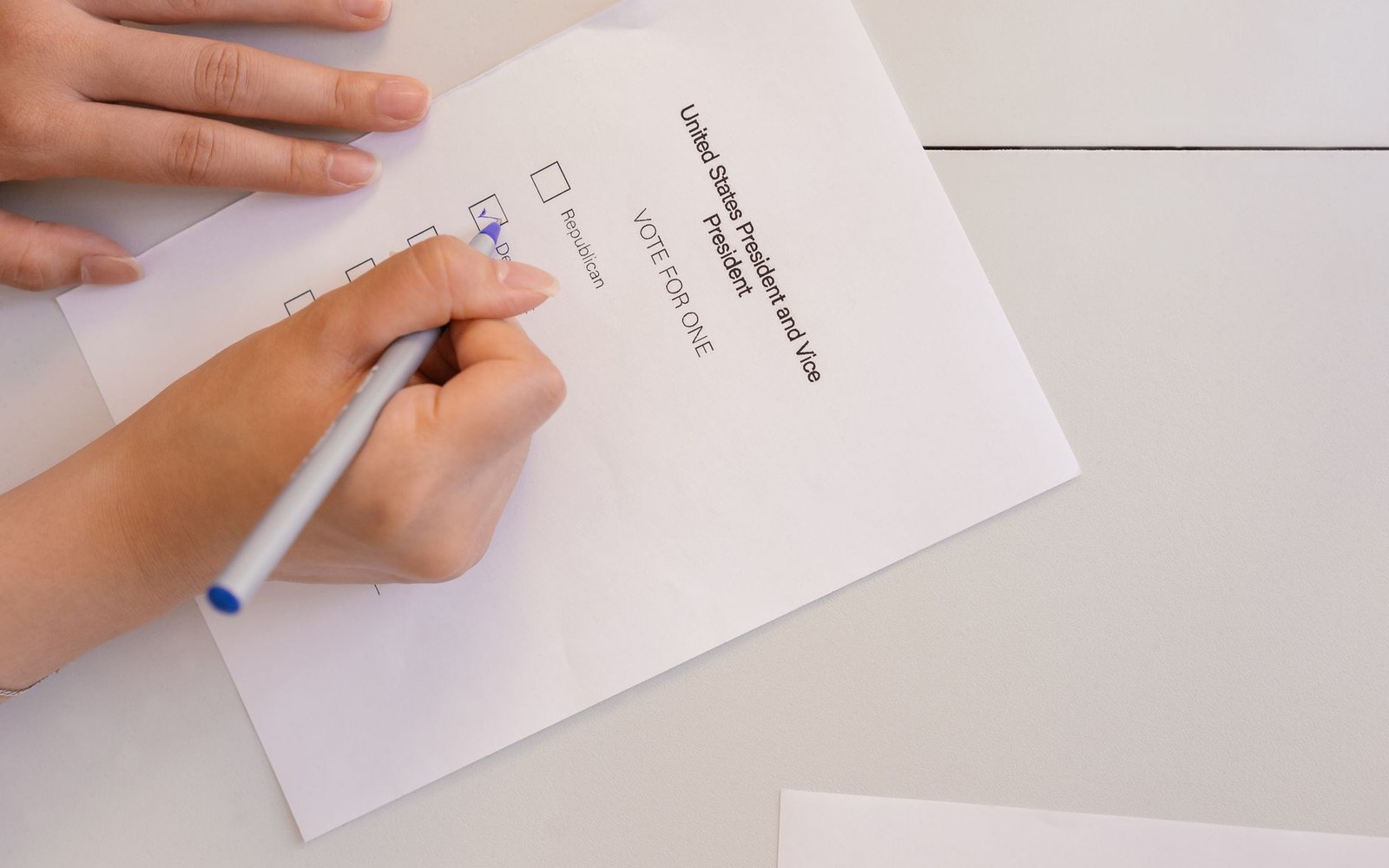A hand marks a checkbox on a presidential and vice presidential election ballot